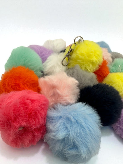 Assortment of fluffy sensory plush balls in various bright colors including pink, blue, yellow, orange, and purple, each with a keychain clip.