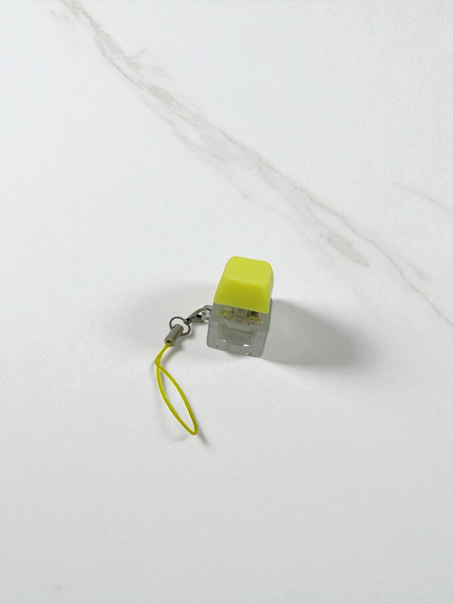 Sensitive Little Souls yellow mechanical keyboard clicker fidget toy with lanyard on white marble surface.